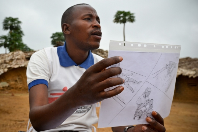 Osvětový pracovník Daniel vysvětluje, jak vypadá malárie u dítěte.