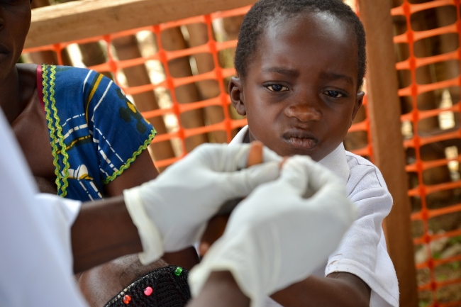 Středisko v Bikenge: Zdravotní bratr odebírá vzorek krve malého pacienta kvůli rychlému testu na malárii.