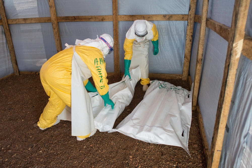 Hygienikové ukládají těla dvou obětí eboly do speciálních vaků. Foto © Sylvain Cherkaoui/Cosmos