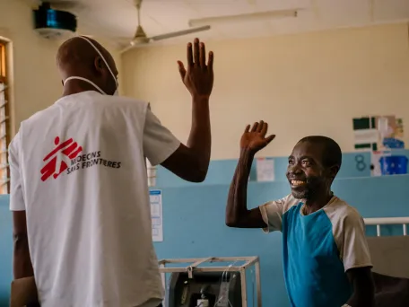 Muž a lékař se na sebe usmějí a jdou si plácnout, Malawi, 2019. Foto: Isabel Corthier / Lékaři bez hranic