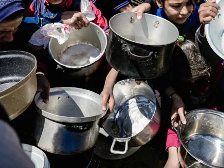 Děti drží prázdné hrnce v komunitní kuchyni na severu Gazy. Písmo Gazy, 2025. Foto: Nour Alsaqa / Lékaři bez hranic