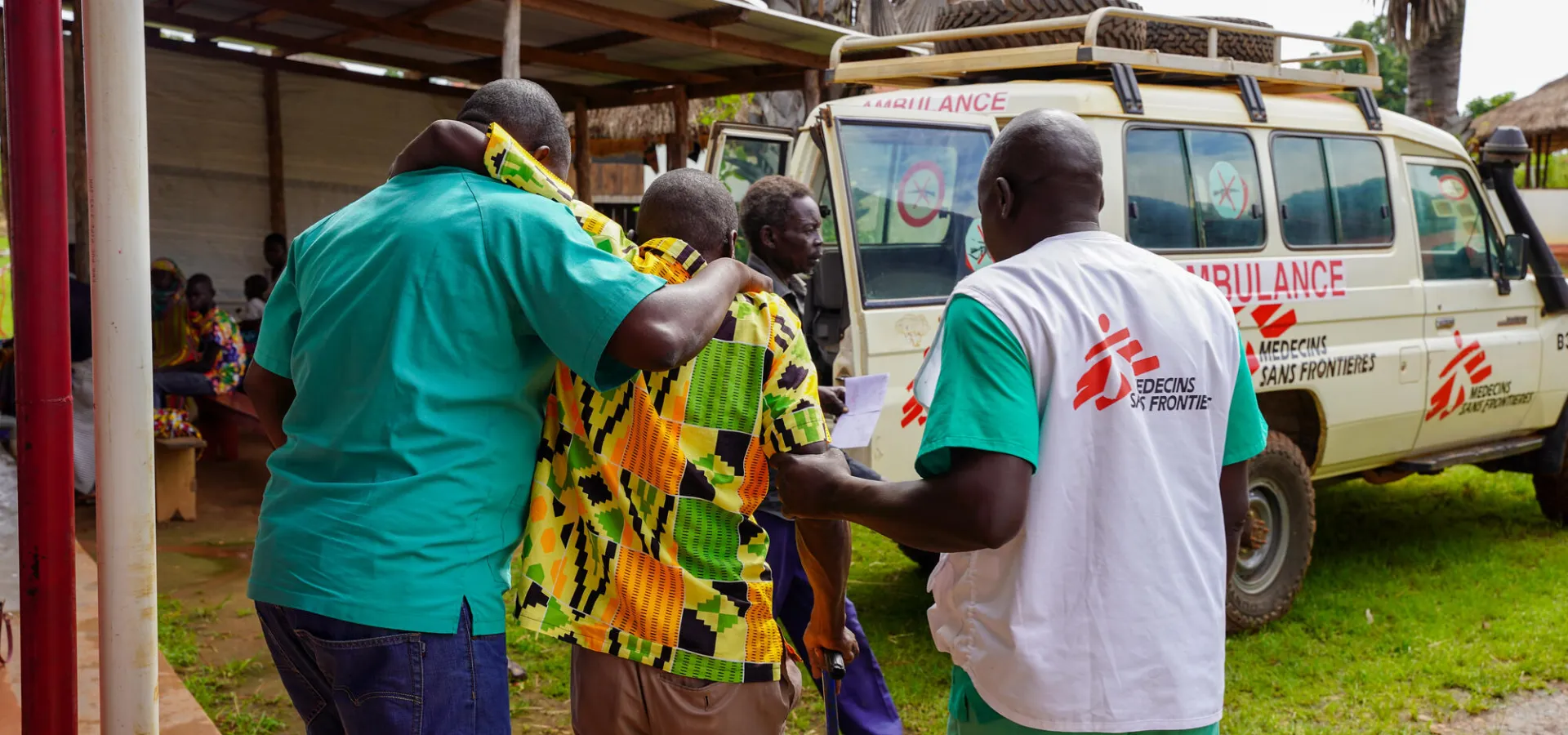 Two MSF medical staff help a patient