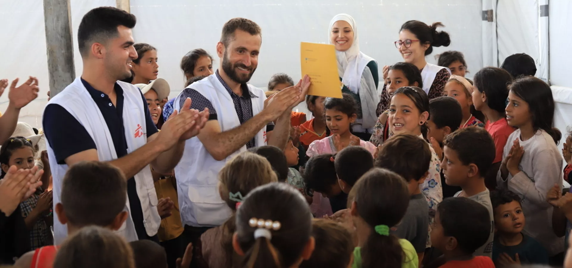 Zaměstnanci MSF obklopeni dětmi, Palestína, 2024. Foto: Mariam Abu Dagga / Lékaři bez hranic
