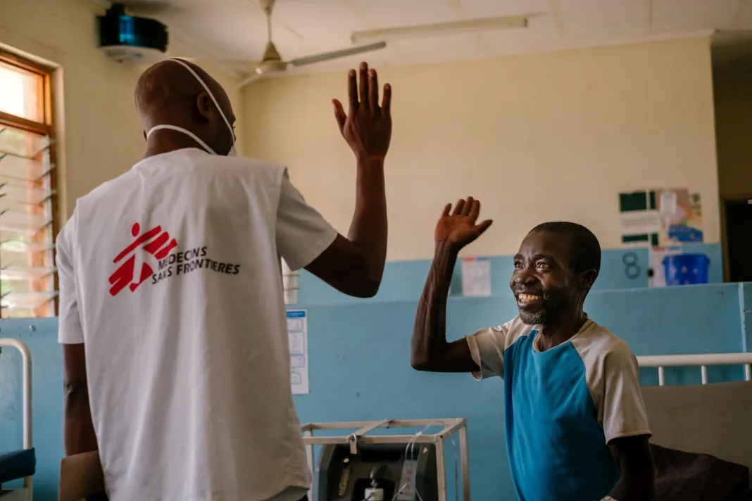 Muž a lékař se na sebe usmějí a jdou si plácnout, Malawi, 2019. Foto: Isabel Corthier / Lékaři bez hranic