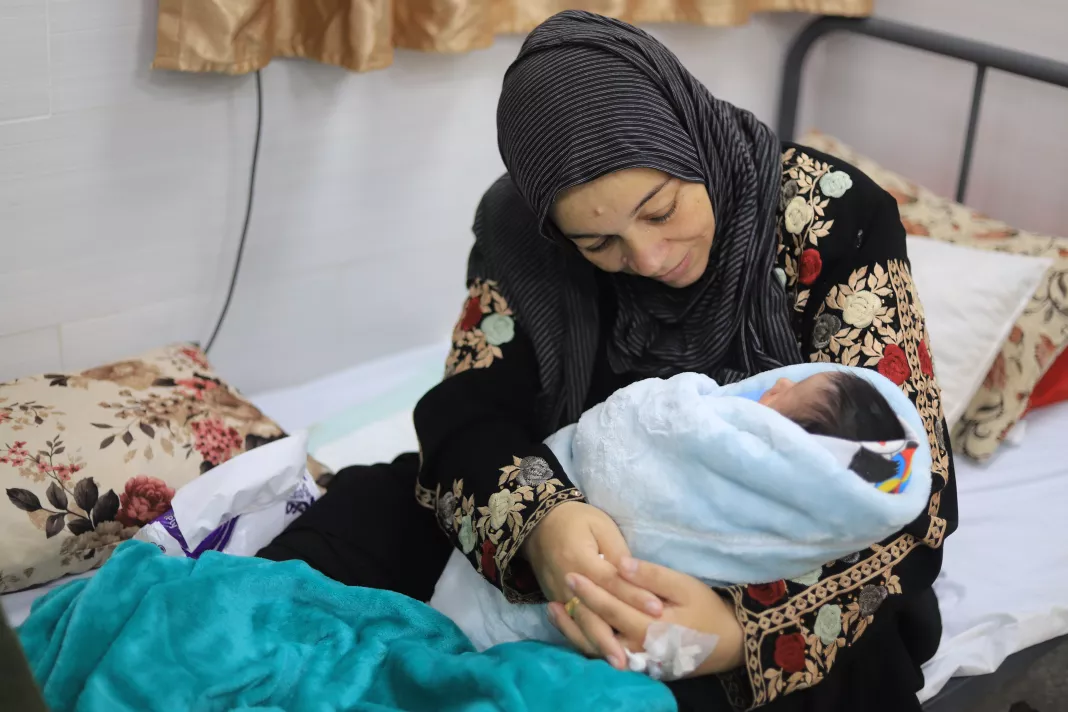 Matka drží své novorozené dítě. Palestina, 2024. Foto: Mariam Abu Dagga / Lékaři bez hranic