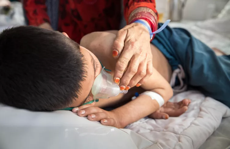 Matka se dotýká svého syna, který má zápal plic a spalničky, Afghánistán, 2023. Foto: Oriane Zerah