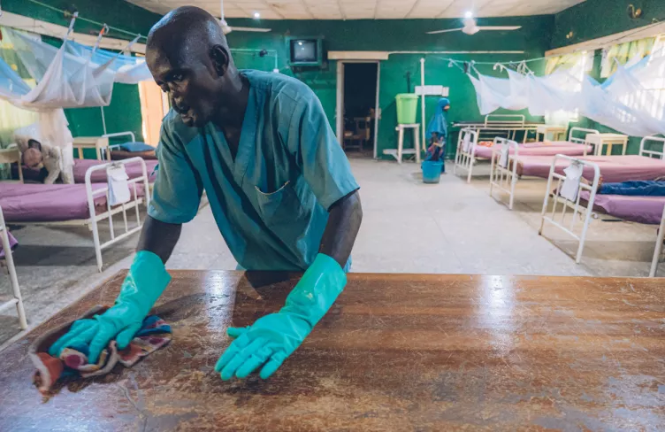 Přeživší nomy a náš kolega utírá plochu v nemocnici, Nigérie, 2023. Foto: Fabrice Caterini / Inediz