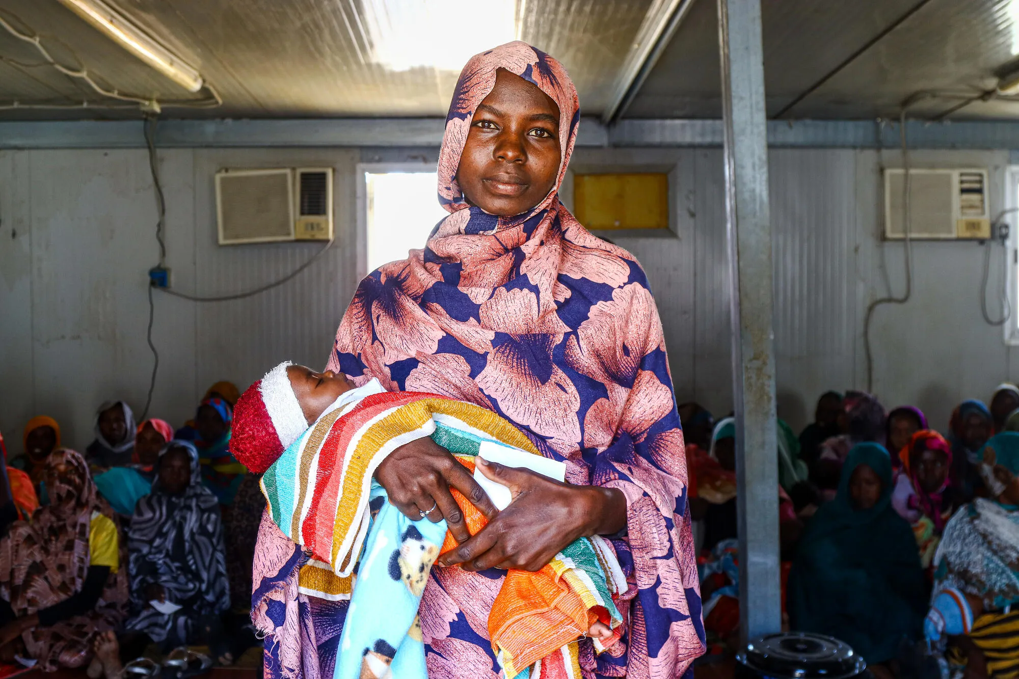 Matka s dítětem ve zdravotním centru tábora Kalma. Súdán, 2024. 